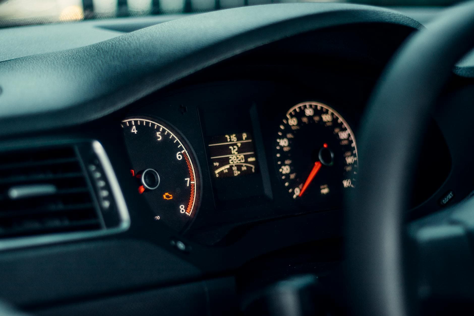 Detailed view of a car's dashboard featuring illuminated gauges and speedometer.